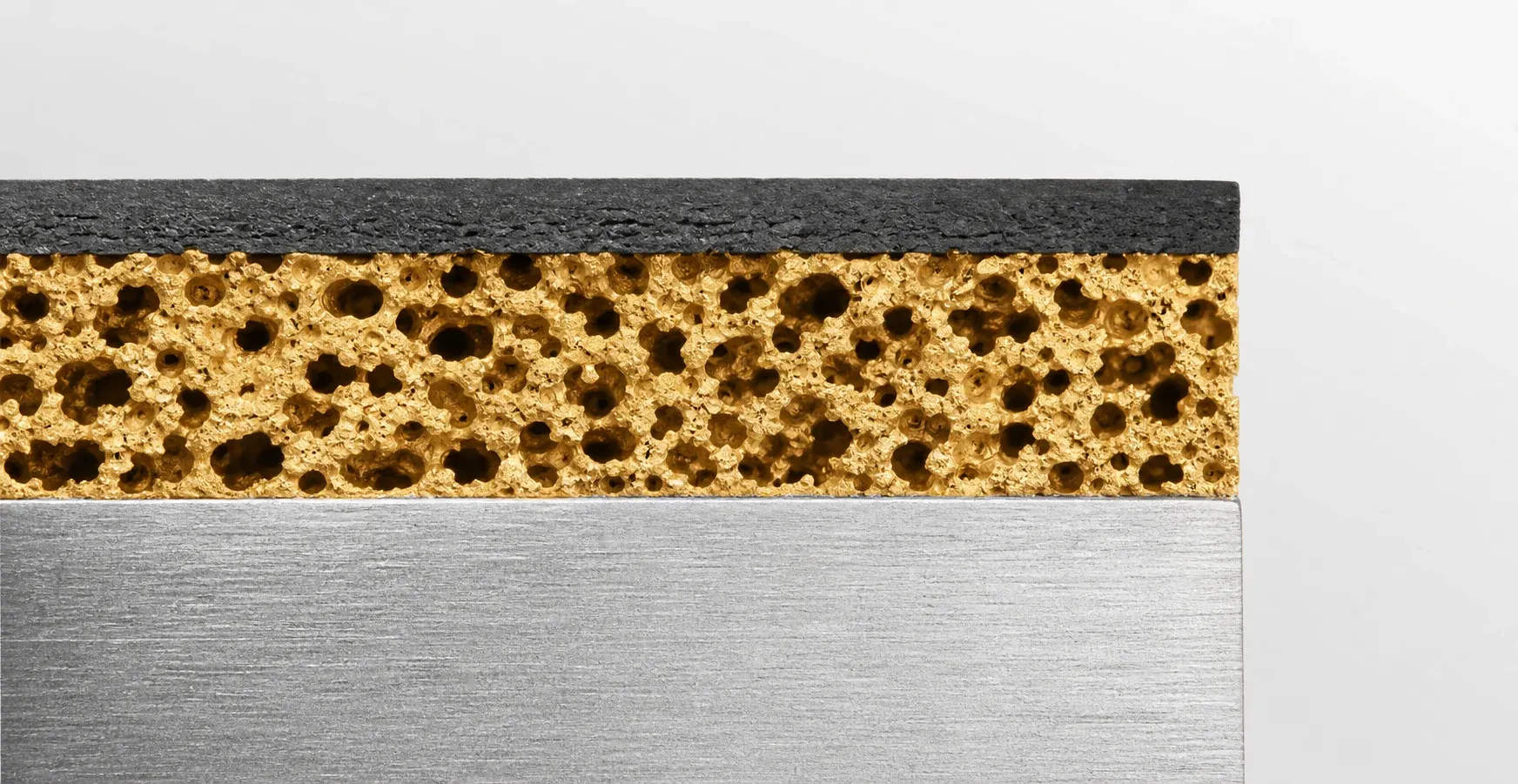 Sezione di una boccola composita in PTFE: supporto in acciaio, bronzo sinterizzato, strato in PTFE